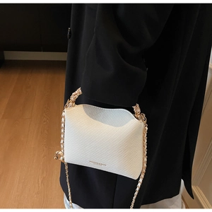 White quilted crossbody bag with gold chain strap shown on model in indoor setting