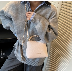 Detail of pink quilted chain bag featuring elegant woven texture and metal strap