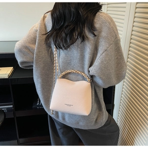 Detail of beige quilted chain bag featuring elegant gold hardware and textured finish