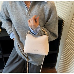 Detail of cream quilted mini bucket bag with gold chain strap and fashion text engraving