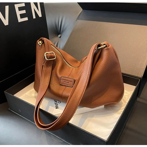 Detail der braunen Ledertasche mit Litschi-Muster und Goldbeschlägen in Geschenkbox