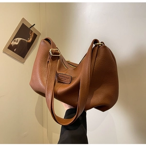 Detail einer braunen Hobo-Tasche mit strukturierter Kiesel-Optik und breitem Schultergurt