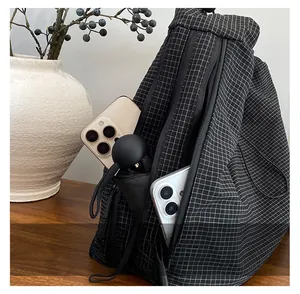 Checkered canvas crossbody bag side pocket showing storage for phone and umbrella