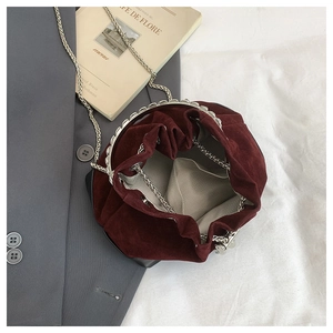 Vue macro du sac seau en velours bordeaux montrant la doublure et la bandoulière chaîne