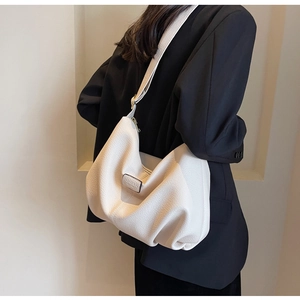 Detailansicht der cremefarbenen Handtasche mit Litschi-Struktur und breitem Gurt