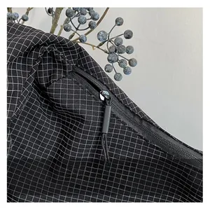 Close-up of smooth black zipper with long puller on black and white checkered canvas bag