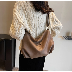 Dunkelbraune Schultertasche aus Leder mit Litschi-Muster am Model im lässigen Pendler-Stil