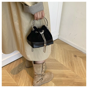 Détail du sac seau noir en daim avec poignée en chaîne argentée et cordon de serrage