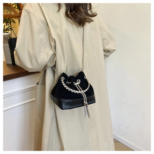 Détail d'un sac seau noir en daim avec anse chaîne argentée et longues franges déco
