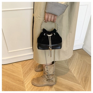Détail du sac seau noir à cordon avec poignée en métal argenté et bandoulière chaîne