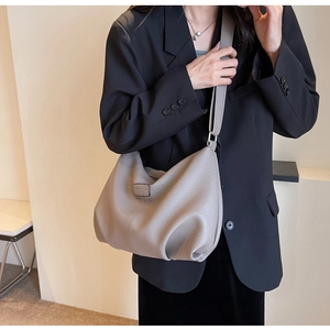 Detailansicht der grauen Schultertasche aus Leder mit modischem Prägeetikett