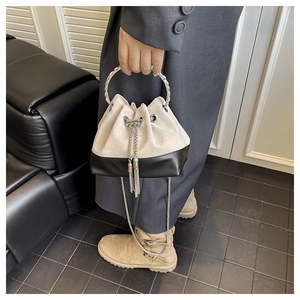 Détail du sac seau bicolore avec poignée anneau argentée et bandoulière chaîne en daim