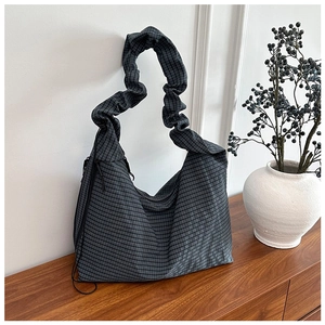 Detail view of a charcoal checkered hobo bag featuring a pleated elastic shoulder strap