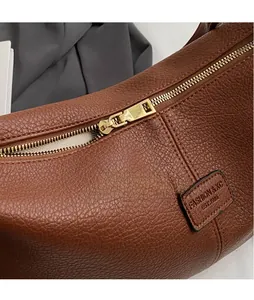 Detailaufnahme der braunen Handtasche aus Leder mit Reißverschluss und Logoprägung