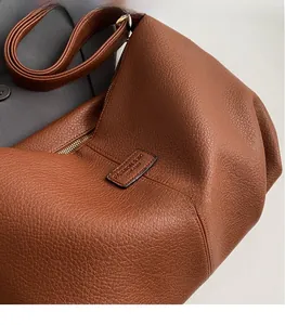 Detailaufnahme der braunen Ledertasche mit Litschi-Maserung und goldenem Reißverschluss