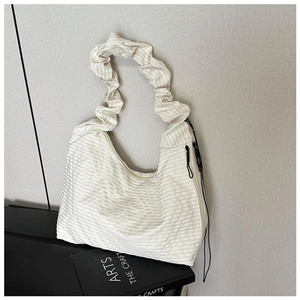 Detail of off-white pleated shoulder bag with fine stripe texture and drawstring accent