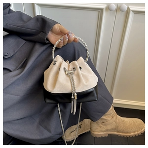 Détail du sac seau bicolore avec poignée anneau argentée et bandoulière chaîne