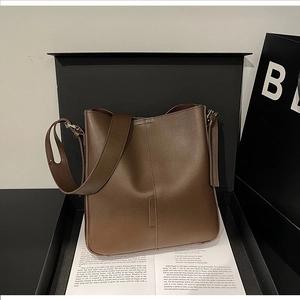 Detailed view of dark brown leather tote bag inside a premium black gift box with book