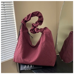 Macro view of the wine red checkered tote bag showing unique ruffled shoulder strap detail