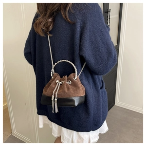 Détail du sac seau bicolore avec poignée en anneau argenté et cordon à pompon en métal