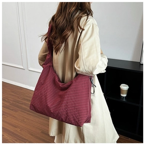 Detail view of red plaid canvas crossbody bag showing texture and side zipper construction