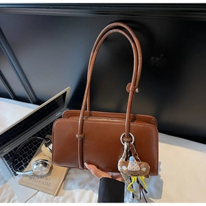 Close-up of deep brown retro shoulder bag with a cute plush bear pendant accessory