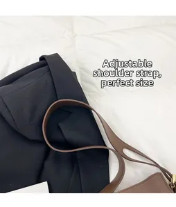 Detail of adjustable shoulder strap with metal buckle on brown faux leather handbag