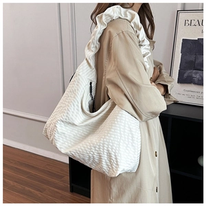 Detail of cream pleated tote bag with large ruffles on the shoulder strap
