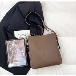 Detail of dark brown leather tote bag with stitching on white quilted background