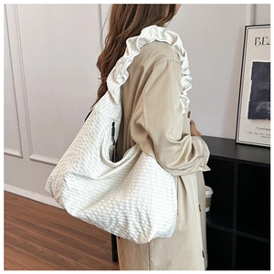 Detail of white pleated tote bag with stylish ruffled shoulder strap on female model