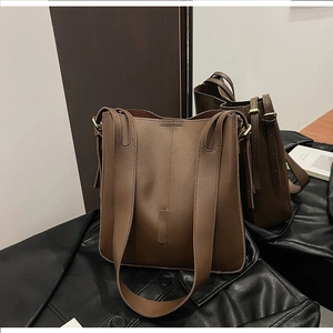 Close-up of deep brown leather tote bag with matte texture and vertical stitching