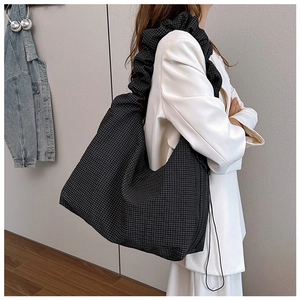 Detail of checkered canvas tote bag with wide pleated strap and side zipper closure