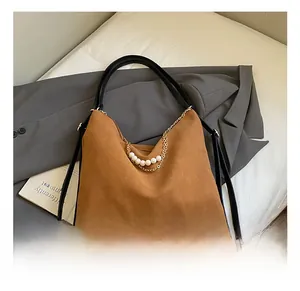 Close-up of brown suede hobo bag featuring pearl and gold chain detail on a suit