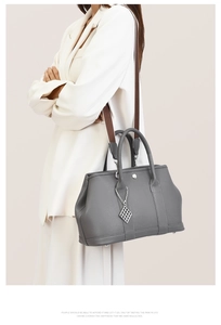Detail of dark grey lychee leather tote bag with wide strap and metallic charm