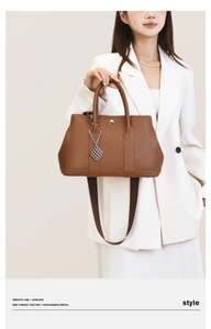 Detail of lychee pattern leather bag with silver metal buckles and wide shoulder strap