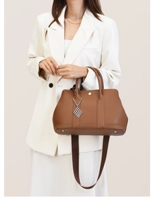 Detail of brown litchi pattern leather tote bag with wide strap and silver pendant