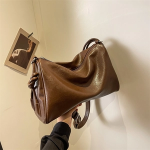 Close-up of vintage brown leather Boston bag featuring detailed knot decor and smooth zipper