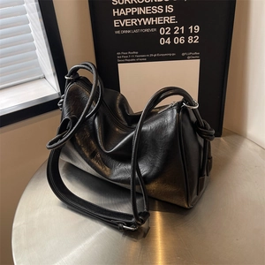 Detail of a vintage black Boston bag with distressed leather texture and knotted straps