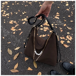 Detail of dark brown hobo shoulder bag with elegant gold chains and pearls