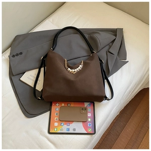 Deep brown large shoulder bag with pearl gold chain shown on a suit with a tablet