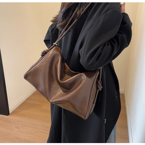 Detail view of brown faux leather Boston bag with retro knot accents and soft texture