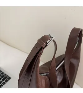 Detail of adjustable metal buckle on brown textured leather shoulder bag strap