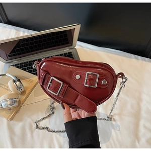 Détail d'un sac cœur en cuir verni bordeaux avec bandoulière en chaîne argentée