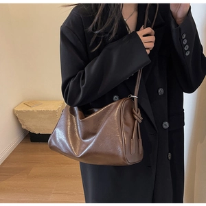 Detail view of brown leather Boston bag showing soft oil-wax texture and knotted side decor
