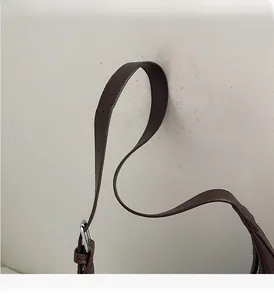 Macro detail of dark brown leather strap with silver adjustable buckle on tote bag