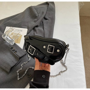 Détail du sac croissant en cuir verni noir avec boucle argentée et chaîne en métal