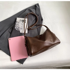 Detail view of deep brown Boston bag with adjustable shoulder strap and decorative knots