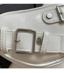 Détail du sac en cuir crème avec boucles et finitions en métal argenté brillant