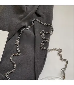 Détail d'une bandoulière chaîne en métal argenté sur un sac blanc à maillons ovales