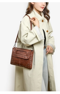 Braune Leder-Umschlagtasche mit silbernen Quadratnieten als Umhängetasche am Modell